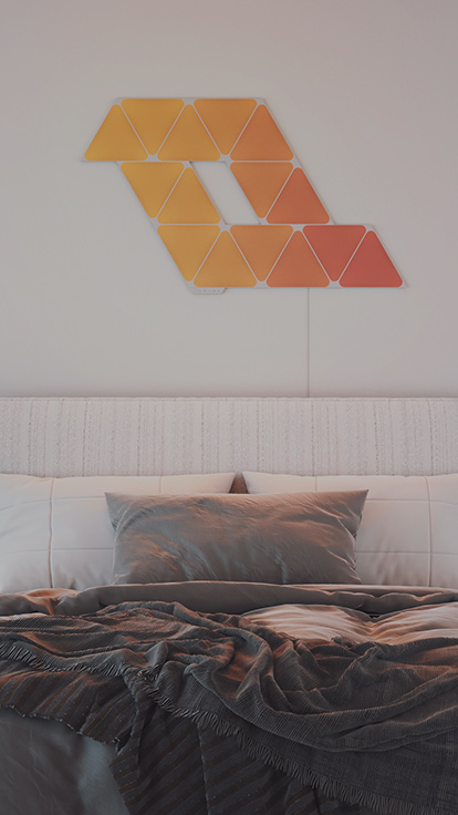 ベッドの上の壁のNanoleaf Shapes Triangles15パネルレイアウトの画像です。 スマートライトパネルは、寝室の照明にぴったり、理想の雰囲気を演出します。