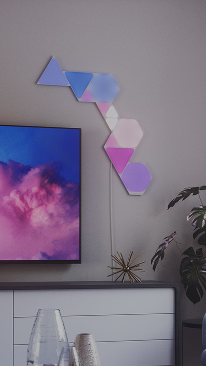 This is an image of Nanoleaf Shapes light panels in a living room. This layout is composed of all 3 shapes in the Nanoleaf Shapes line. The RGB light panels are connected with each other using linkers and have over 16 million colors.