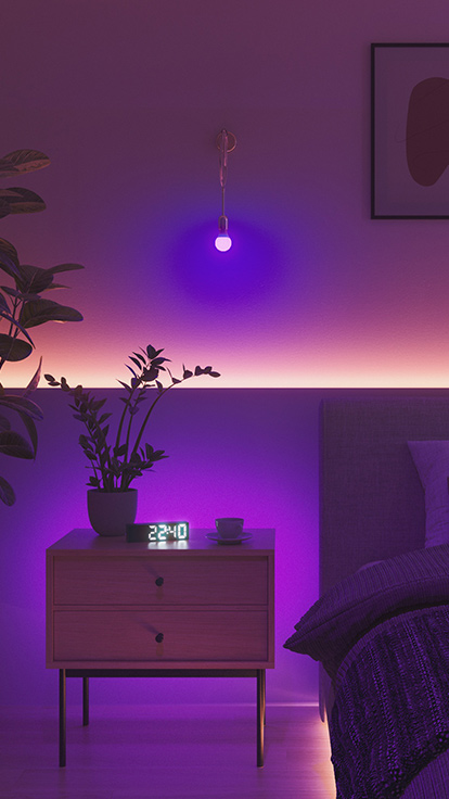 ベッドルームにあるNanoleaf Essentials Bulbの画像です。 ベッドとナイトスタンドの間の壁に設置された照明は、寝室で理想の雰囲気を演出するのにぴったりです。