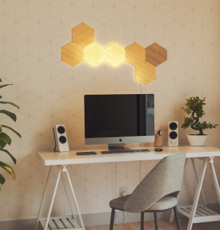 コンピューターの上の壁に取り付けたパネル7枚からなるNanoleaf Elements Wood Look Hexagonsのレイアウトの画像です。 組み立て式のスマートライトパネルがユニークなデザインを作り、自然な光であなたの空間を灯します。 パーソナルオフィスを彩るのにぴったりのライト。