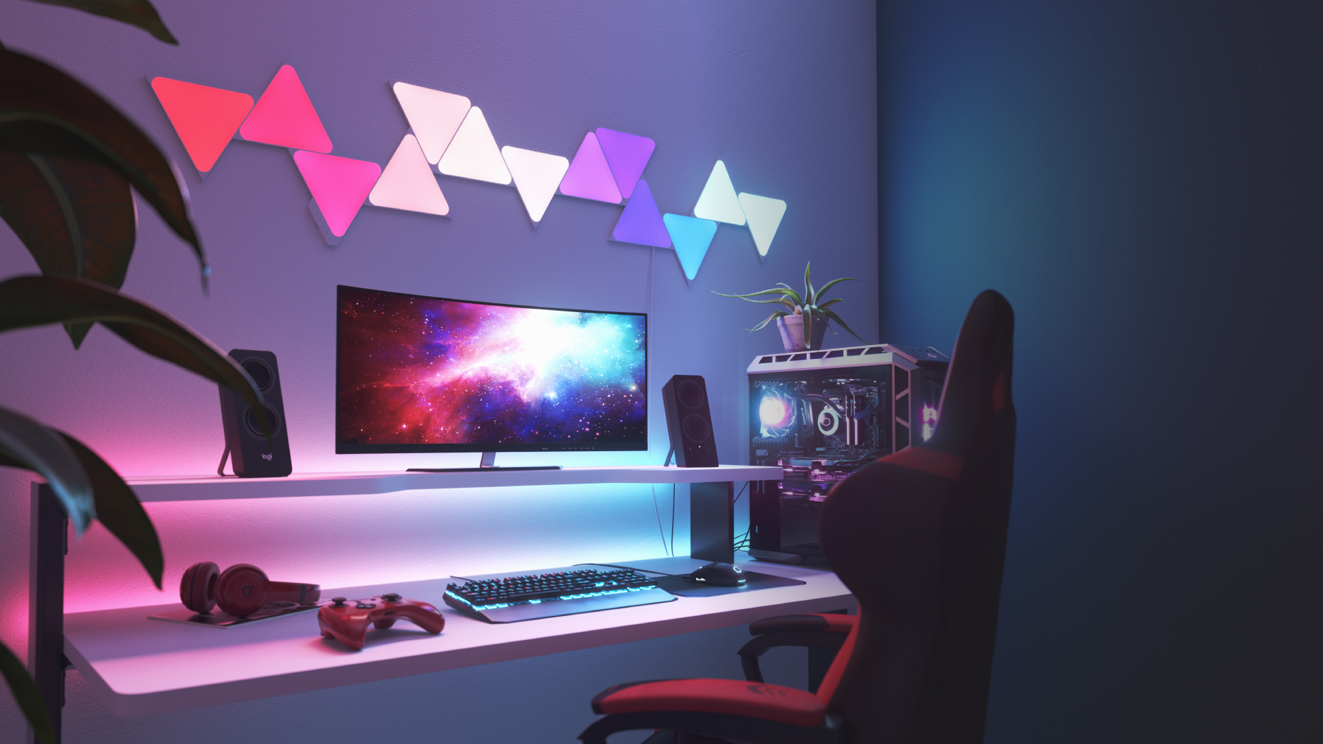 This is an image of a 13 panel layout of Nanoleaf Shapes Triangles on the wall above the desk and behind the monitor in a gaming battlestation. These color changing lights have over 16 million colors and are perfect for the gamer in your home.